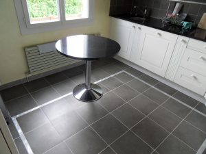 La cuisine avec son sol carrelé avec motifs en aluminium brossés intégrés